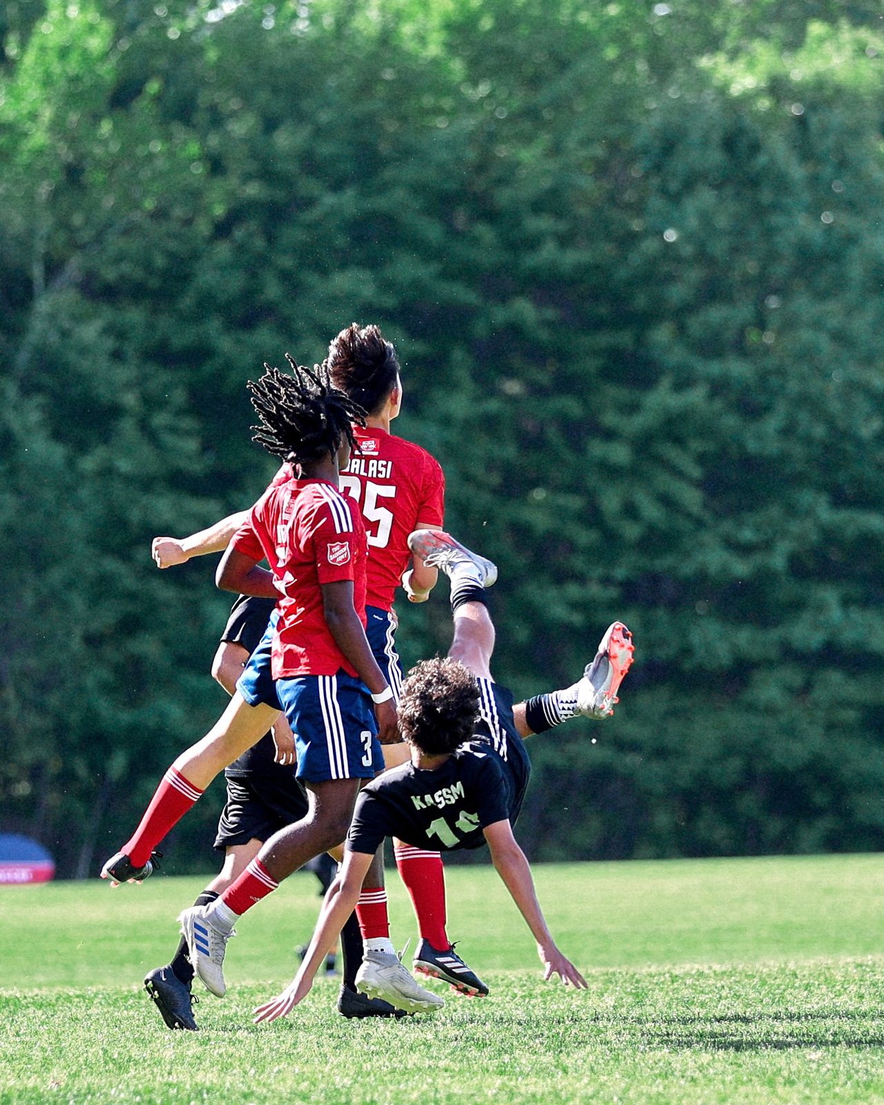 Youth soccer player mid bicycle kick as two defenders jump for the ball
